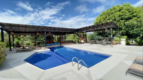 an outdoor swimming pool with a wooden pergola and a swimming poolvisor at Hacienda Hosteria Chorlavi in Ibarra