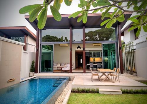 a house with a swimming pool and a dining area at Horizon Vista Pool Villa Family Retreat Bangtao in Phuket