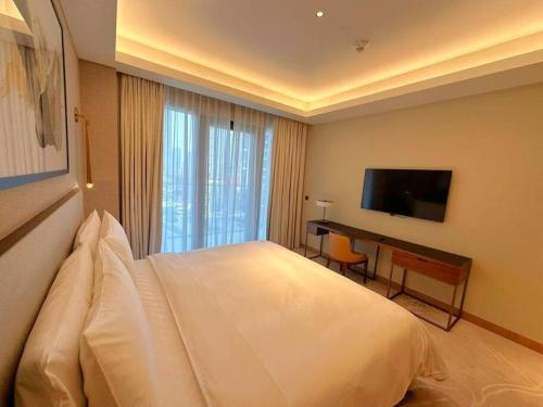 a bedroom with a bed and a desk and a television at Dreamy 2BR Haven, Downtown Bliss in Dubai