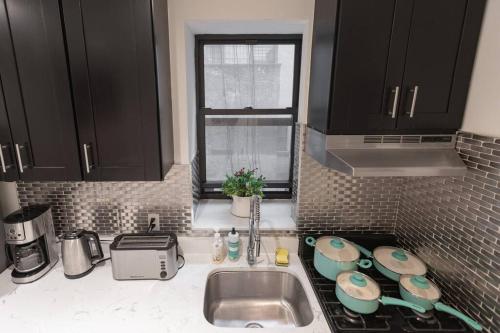 a kitchen with black cabinets and a sink and a window at Magnificent 5BR apartment in NYC! in New York