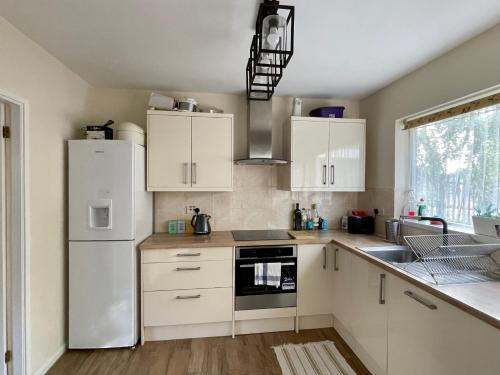 a kitchen with white cabinets and a white refrigerator at CROYDON Spacious 3 Bedroom Family House in Addington