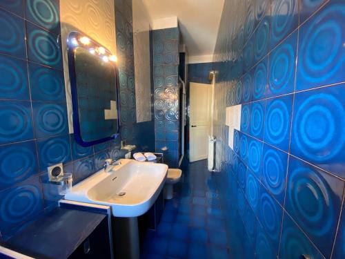 ブレシアにあるAppartamenti Leonardoの青いタイル張りの壁、洗面台付きのバスルーム