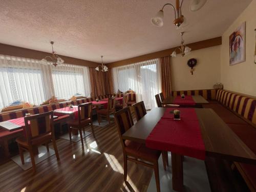 ein Esszimmer mit Tischen, Stühlen und Fenstern in der Unterkunft Gästeheim Lederle in Jerzens