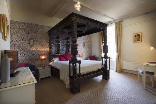 a bedroom with a large bed with a wooden canopy at The George Hotel & Brasserie, Cranbrook in Cranbrook