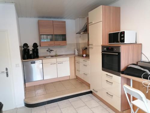 eine Küche mit weißen Schränken und schwarzen Geräten in der Unterkunft Ferienanlage - Am Moselufer in Kövenig