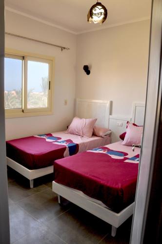 a bedroom with two beds with red sheets at Cozy apartments in Coraya Bay