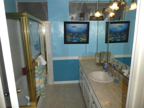 y baño azul con lavabo y ducha. en Nice Northridge 4-2-2 Pool home near CSUN and Pierce College en Northridge