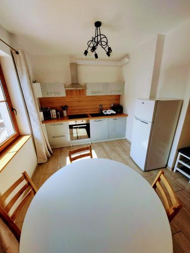 kuchnia z białym stołem i białą lodówką w obiekcie Drzewna Apartamenty-Kupiecka 66A w Zielonej Górze