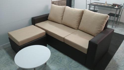 un sofá con 2 almohadas y un taburete en una habitación en Departamento Cerro Catedral en Neuquén