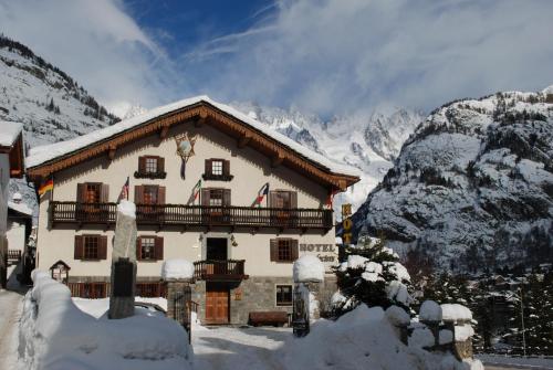 a house in the snow with mountains in the background at Hotel Des Glaciers in Courmayeur