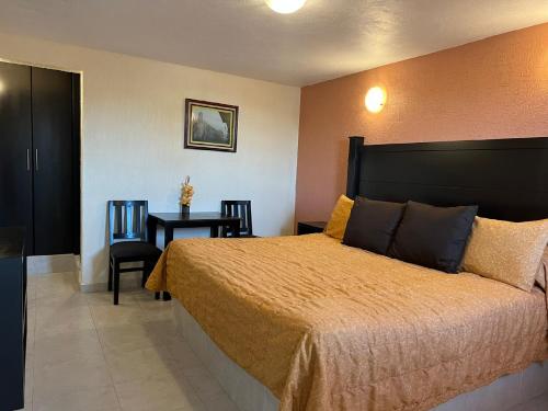 a bedroom with a bed and a table with chairs at Hotel Posada Real in Mineral del Monte
