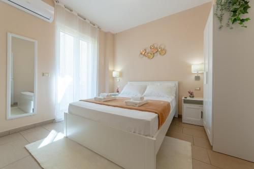 a white bedroom with a large bed and a window at L'Affaccio Rooms - Lungomare Gallipoli in Gallipoli