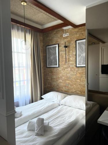a bedroom with a white bed with a brick wall at Hotel Zlatni Bor in Sokolac