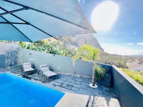 a pool with two chairs and a palm tree on a house at Haus am Meer by Your Madeira Rentals in Paul do Mar