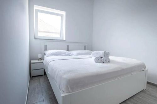 a white bedroom with a large white bed with a window at 2022 Central Apartment Maribor (Garden + Parking) in Maribor
