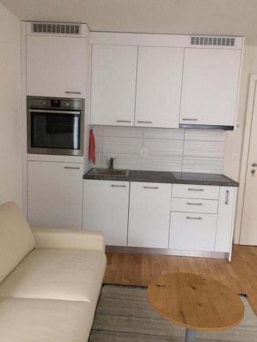 uma cozinha com armários brancos, um sofá e uma mesa em 2 Zimmer Appartement em Winterthur