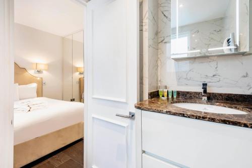 ein Bad mit einem Waschbecken und einem Bett in der Unterkunft Luxury 2 bed in front of Museums in London