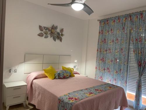Un dormitorio con una cama con almohadas amarillas y una ventana en Apartamento del Toyo, en Almería