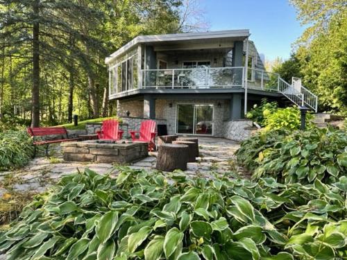 a large house with red chairs in a garden at Waterfront Cottage in Muskoka in Severn