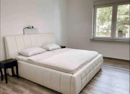 1 cama blanca grande en una habitación con ventana en Maribor Central Apartment (Garden + Free Parking) en Maribor