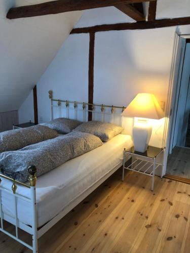 a bedroom with a bed and a lamp on a wooden floor at Byhus-lejlighed med sjæl og privat gårdhave in Hurup