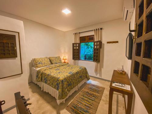 a bedroom with a bed and a table and a window at Maruê Guesthouse Porto de Pedras in Pôrto de Pedras