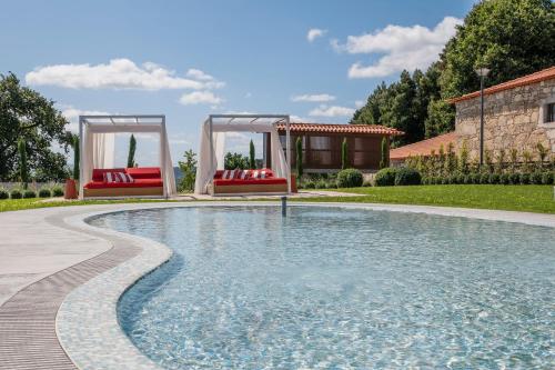 a swimming pool with two red chairs in a yard at Solar de Vila Meã in Barcelos