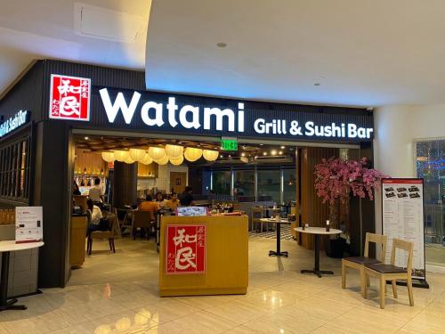 a restaurant with a sign for a grill and sushi bar at Elegant 2BR, 2 BA Suite Beside Eastwood Mall in Manila