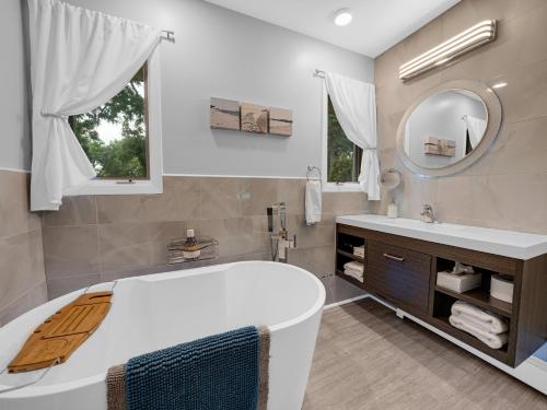 a bathroom with a tub and a sink and a mirror at Coastal Suite - Seacliff Beach Suites in Leamington
