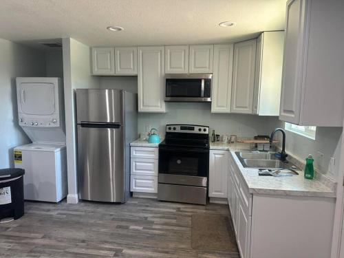 una cocina con armarios blancos y electrodomésticos de acero inoxidable en Guest house near UCD Med. Center, en Sacramento