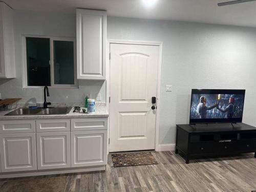 a kitchen with white cabinets and a tv on a door at Guest house near UCD Med. Center in Sacramento