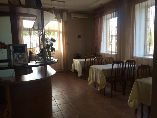 a dining room with two tables and chairs and windows at Altyn Adam Hotel in Pavlodar