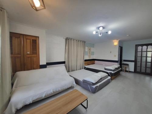a bedroom with two beds and a table at Morning Beach Pension in Jeju
