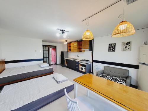 a room with two beds and a table and a kitchen at Morning Beach Pension in Jeju