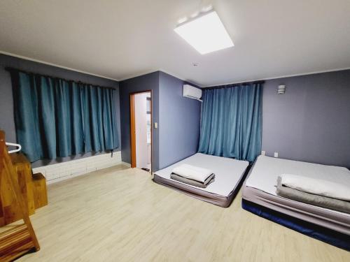 a room with two beds and blue walls at Morning Beach Pension in Jeju