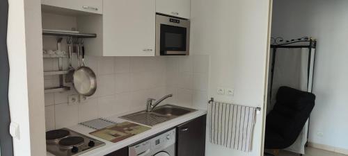 une petite cuisine avec un évier et un micro-ondes dans l'établissement Appartement lumineux à Beausoleil (proche Monaco), à Beausoleil