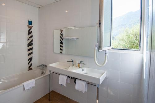 La salle de bains blanche est pourvue d'un lavabo, d'une baignoire et d'une fenêtre. dans l'établissement Hotel Kalliste, à Porto Ota