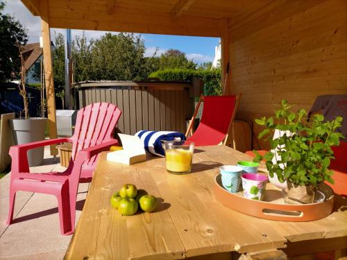 uma mesa de madeira com maçãs e 2 cadeiras num pátio em Maison du petit p(a)in em Cucq