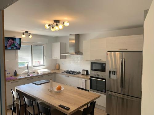 a kitchen with a table and a stainless steel refrigerator at Maison calme/Chambre privée/Clim+TV/Pétit dejeuner inclu/tout confort in Nevers