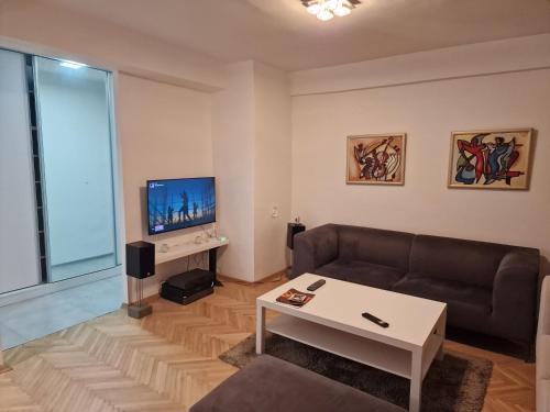 a living room with a couch and a tv at Bright, modern - 2 bedroom condo in Skopje