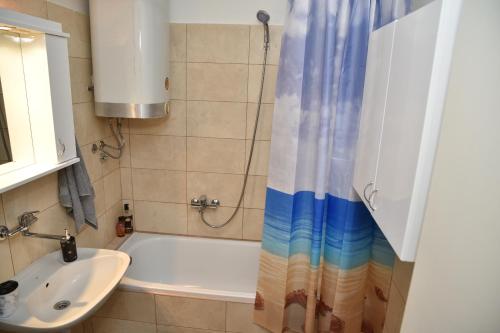uma casa de banho com uma banheira, um lavatório e um chuveiro em ENA apartman em Kraljevo