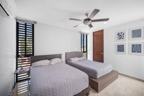 een slaapkamer met 2 bedden en een plafondventilator bij Sunny Mérida Getaway: Spacious 3BR with Pool in Mérida