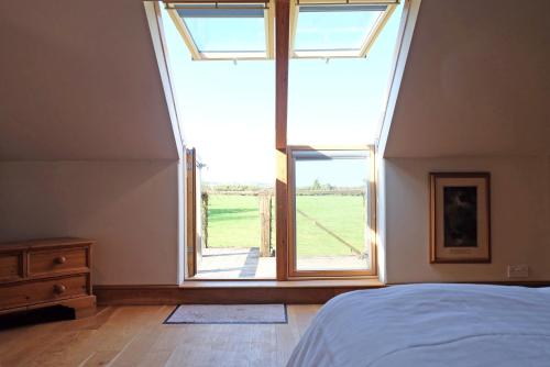 a bedroom with a bed and a large window at The Ox House in Chewton Mendip