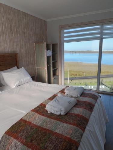 1 dormitorio con 1 cama con 2 almohadas y ventana en Lodge Puerto Koupo, en Carahuo