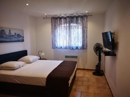 Un dormitorio con una cama y un televisor y una ventana. en E Cabane, en Rottani