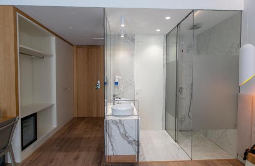 a bathroom with a glass shower with a sink at Empire Beach Resort ADULTS ONLY in Dhërmi