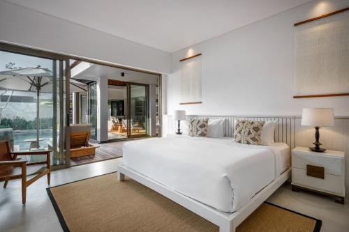 biała sypialnia z dużym łóżkiem i stołem w obiekcie Villa Ria Bali w mieście Seminyak