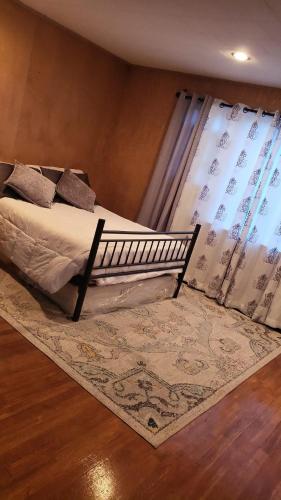 1 dormitorio con 1 cama con alfombra y ventana en Cozy and Sweet home en Lynn
