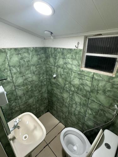 La salle de bains verte est pourvue d'un lavabo et de toilettes. dans l'établissement Casa baixinha, à Ubajara