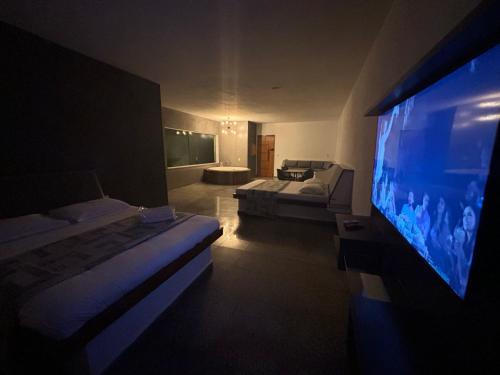 a living room with a large screen tv and a bedroom at Gran Luha Motel, Hotel e Chalés in Brotas